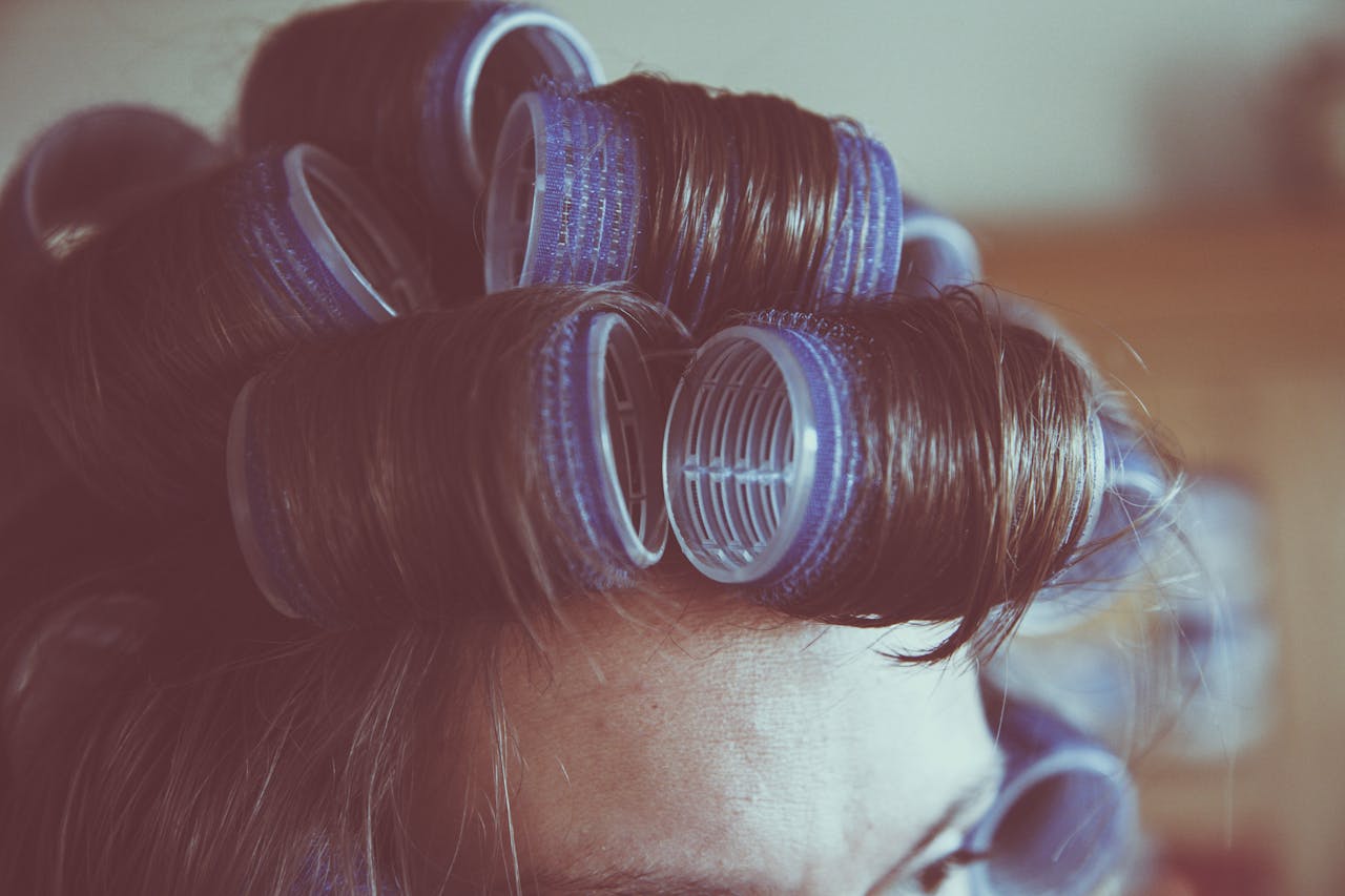 about-01 Vintage-style close-up of a woman's hair in curlers, emphasizing retro hair styling.