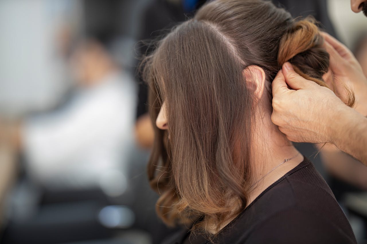 gallery-3 Close-up of a hairstylist creating an elegant hairstyle for a woman in a salon.