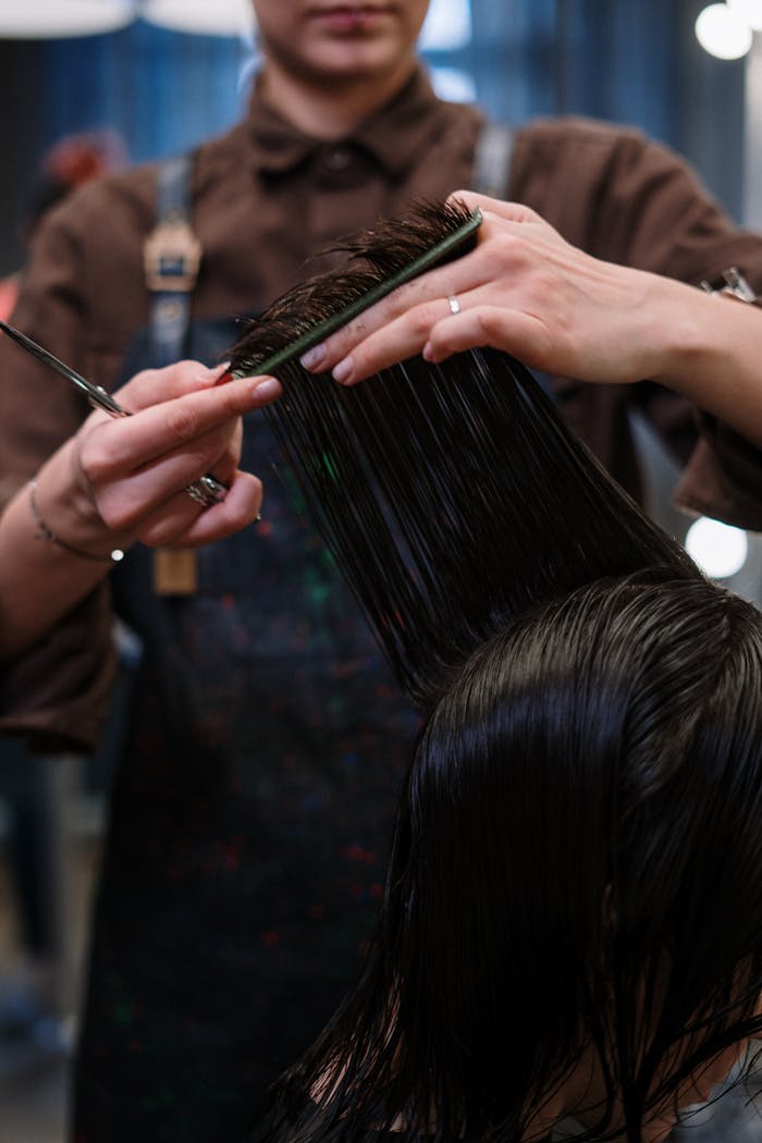 gallery-1 Close-up of a hairstylist cutting wet hair in a professional salon.